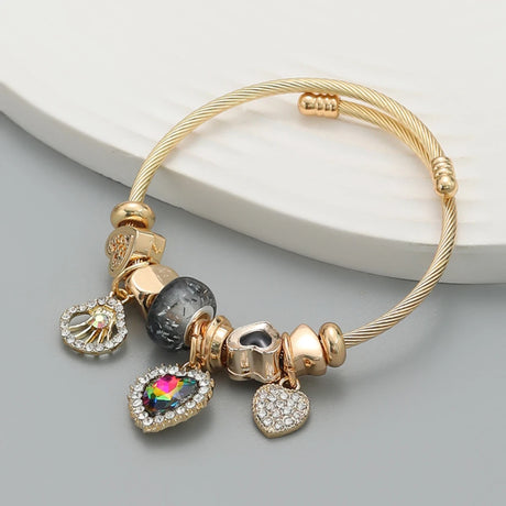 Gold bracelet with various charms on a light gray surface