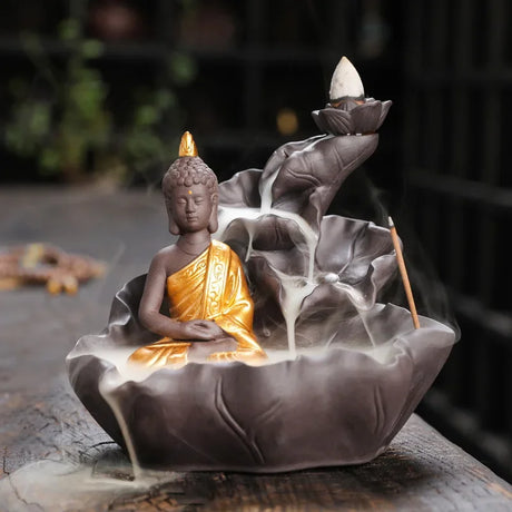 Decorative incense burner with a Buddha figure and backflow incense on a wooden surface.