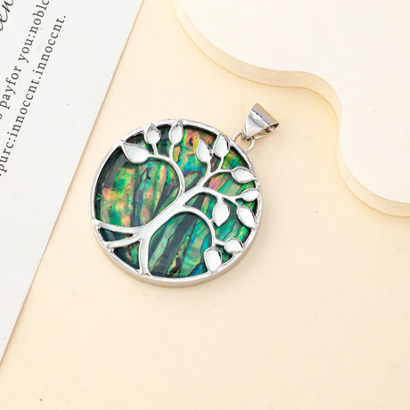 Silver pendant with green and brown inlaid design on a beige surface