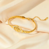 Gold bracelet with intricate design on a beige fabric background