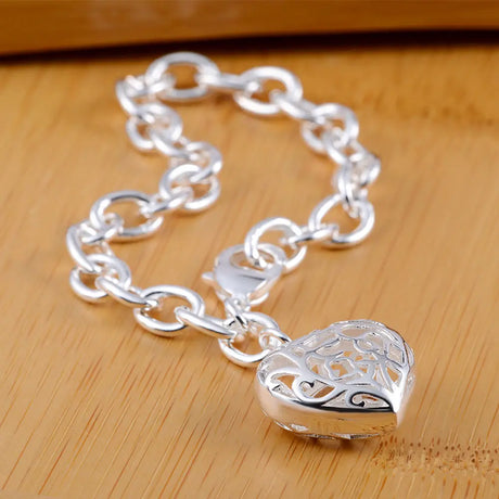 Silver chain bracelet with a heart-shaped clasp on a wooden surface