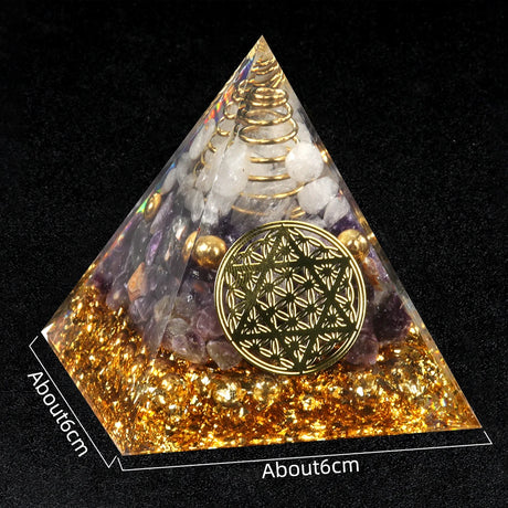 Pyramid-shaped decorative item with gold and multicolored stones on a black background