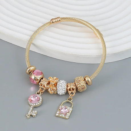 Gold bracelet with colorful charms on a gray surface