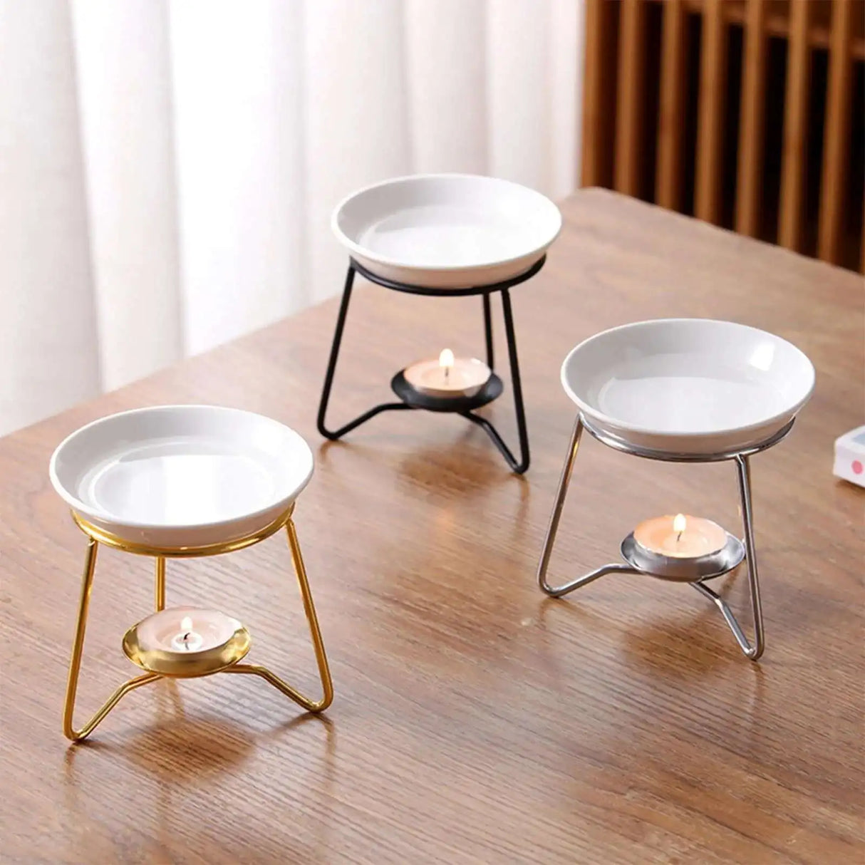 Three white candle holders with different base colors on a wooden surface.