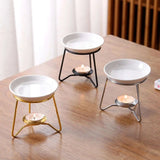 Three white candle holders with different base colors on a wooden surface.