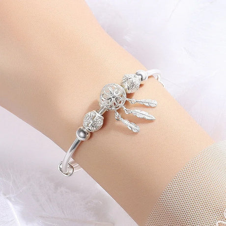 Silver bracelet with decorative elements on a wrist against a white background