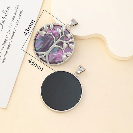 Tree of life pendant with purple inlay and black round pendant on a beige background