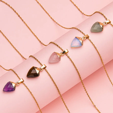 Gold necklaces with colorful gemstones on a pink background