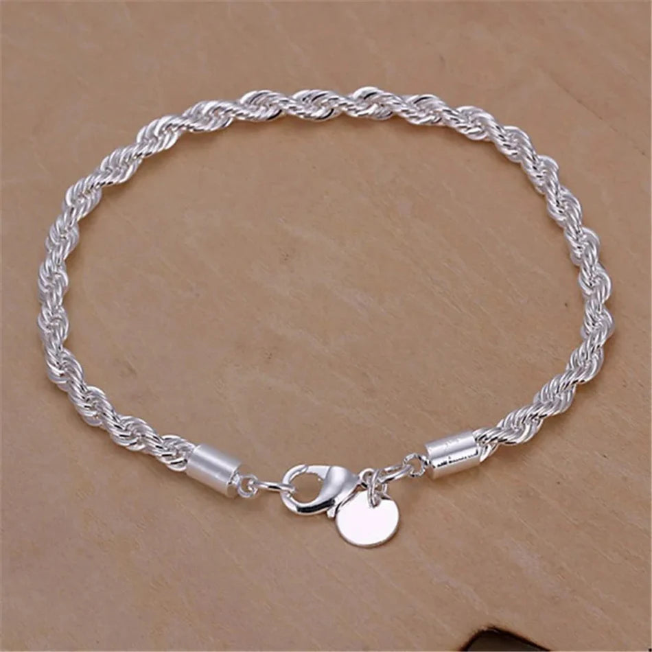 Silver rope chain bracelet with a round charm on a beige background