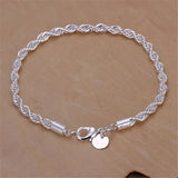 Silver rope chain bracelet with a round charm on a beige background