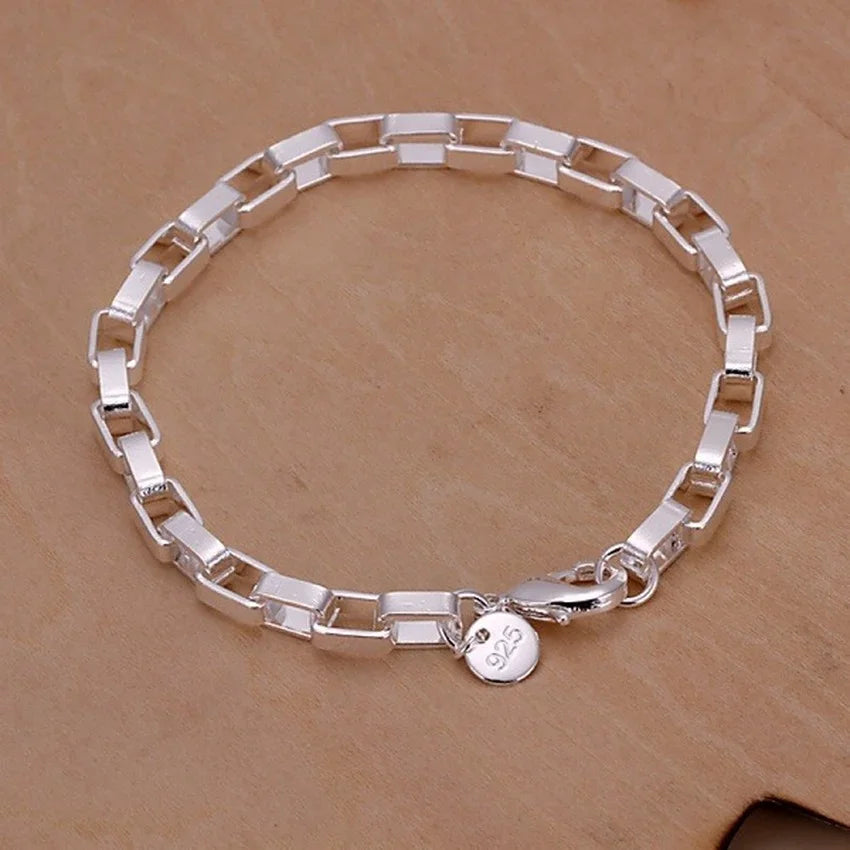 Silver bracelet with a round charm on a brown background