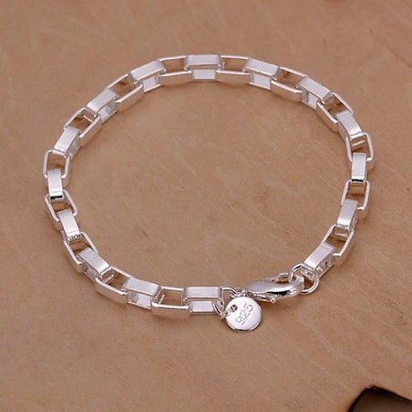 Silver bracelet with a round charm on a brown background