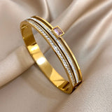 Gold bracelet with a pink gemstone on a beige fabric background