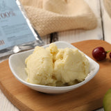 Two scoops of vanilla ice cream in a white bowl on a wooden cutting board.