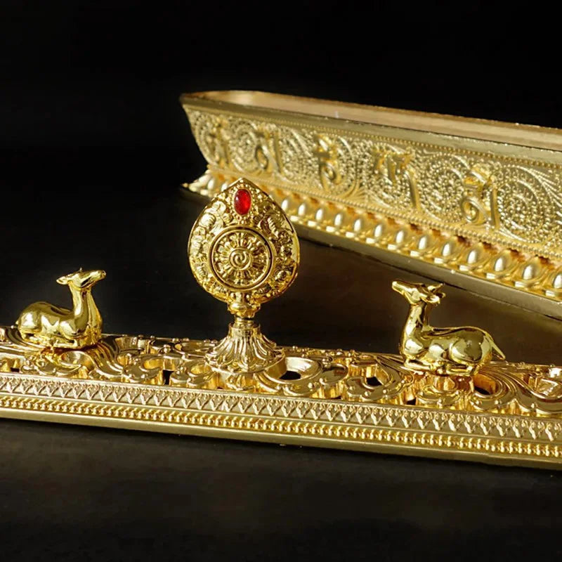 Decorative gold object with intricate designs and small figures on a black background