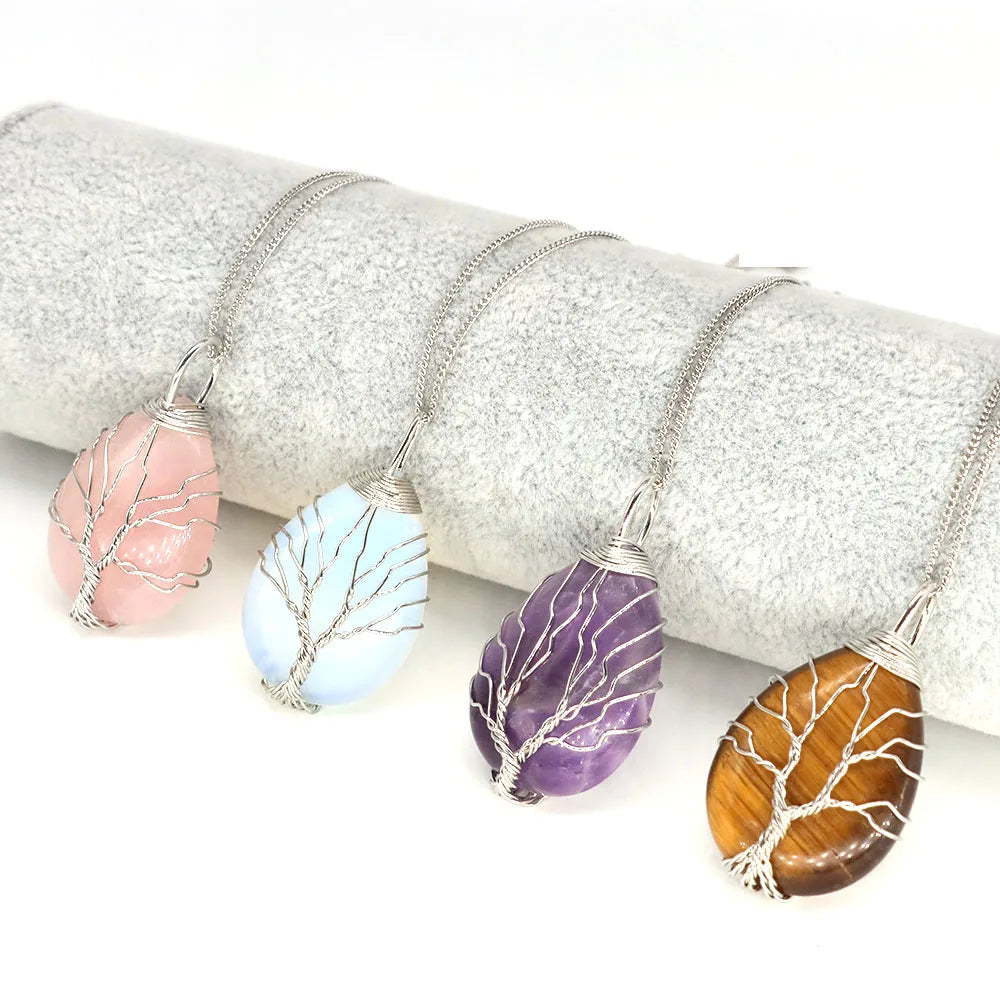Four tree of life pendants in different colors on a white background