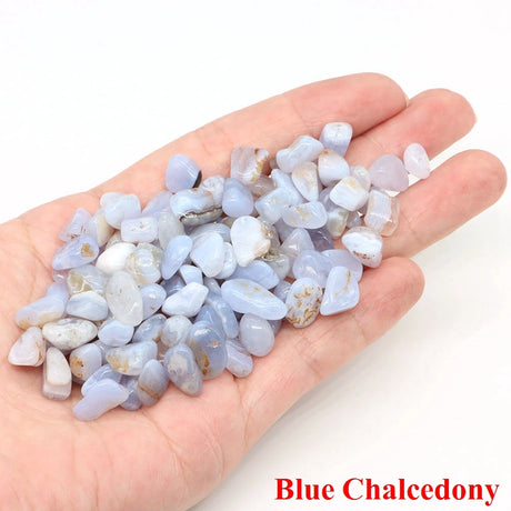 Hand holding a small pile of blue chalcedony stones on a white background