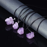 Purple crystal pendants on black strings against a dark background