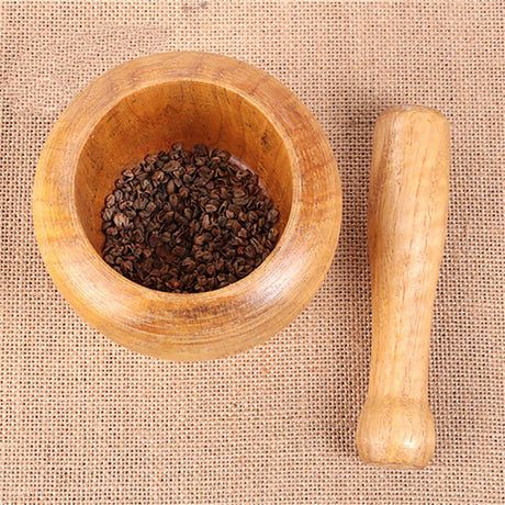 Wooden mortar and pestle with dried herbs on a textured fabric background