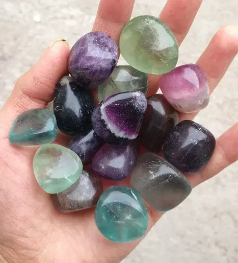 Hand holding a collection of multicolored gemstones.