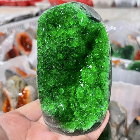 Green crystal held in a hand with a blurred background
