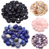 Collection of different colored stones including black, multicolored, pink, blue, and purple on a white background.