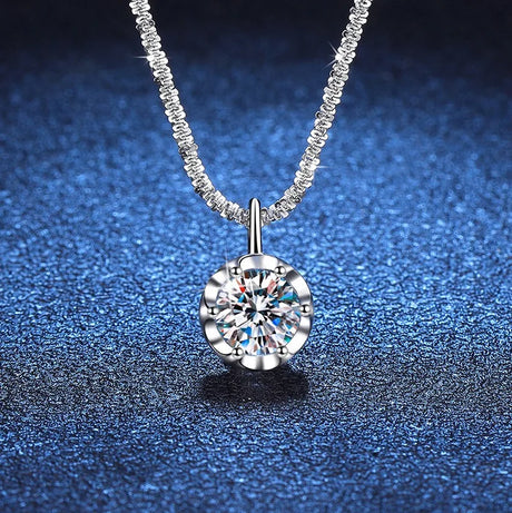 Silver necklace with a round diamond pendant on a blue textured background