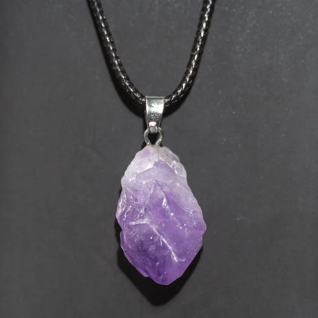 Purple crystal pendant on a black cord against a dark background