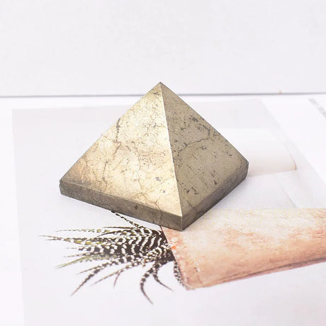 Pyramidal stone on a white surface with a feather