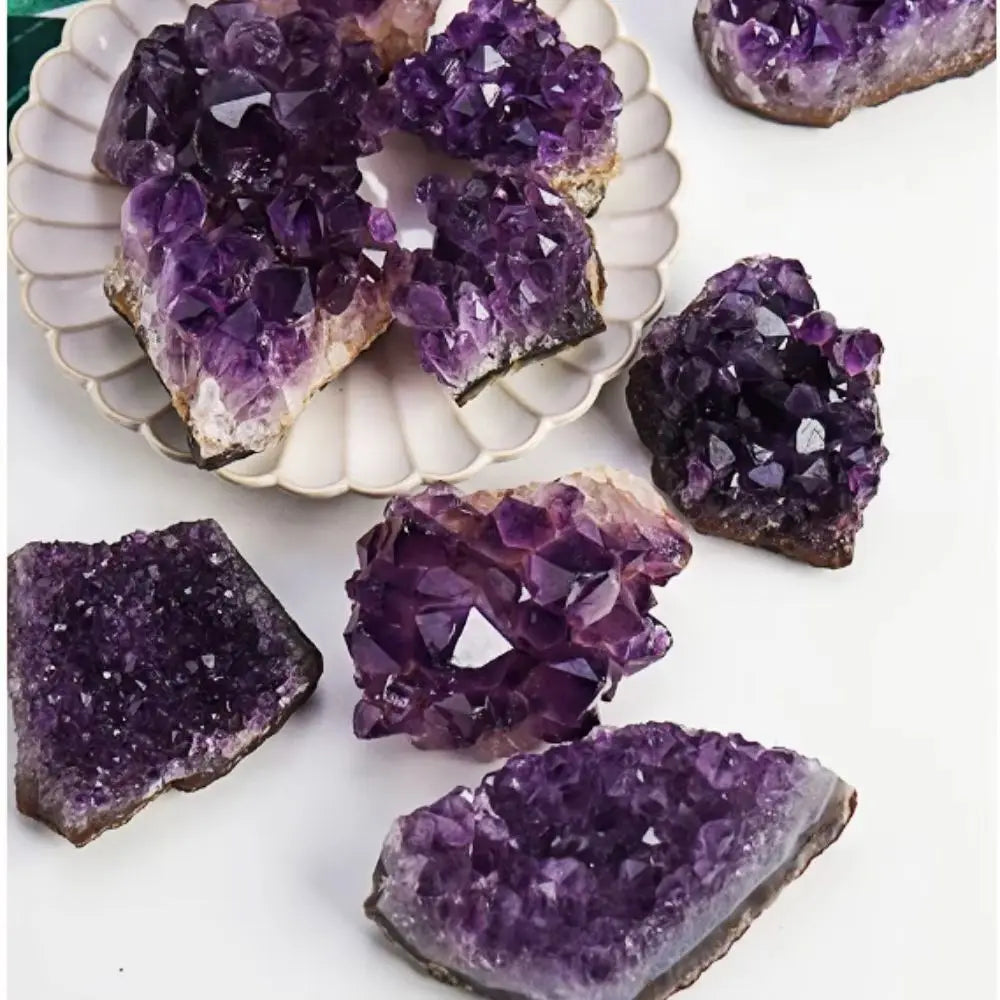 Amethyst crystal clusters on a white surface with a decorative plate.