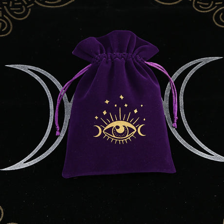 Purple drawstring bag with a gold eye symbol on a black background with moon designs.