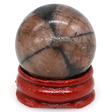 Polished stone sphere on a red stand against a white background