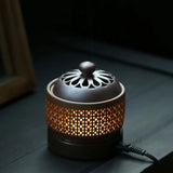 Ceramic incense burner with intricate design on a dark surface