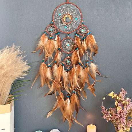 Dreamcatcher with feathers and beads on a gray wall with decorative elements.