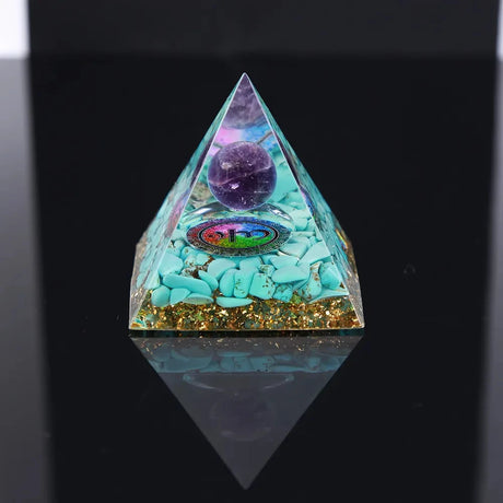 Pyramid-shaped crystal with colorful stones and a purple sphere on a black background