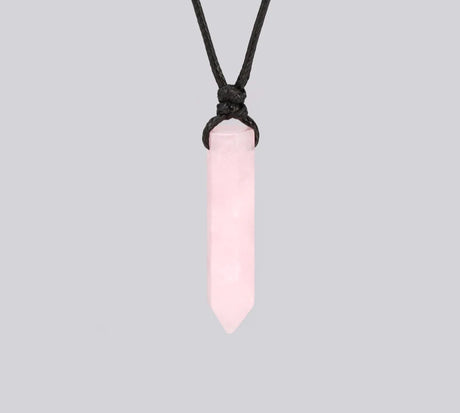 Pink crystal pendant on a black cord against a light gray background