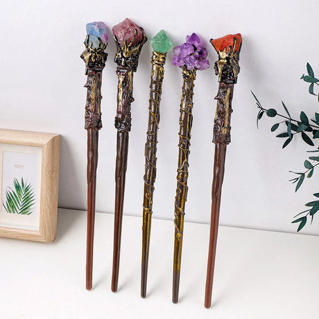 Five decorative wands with colored crystal tops on a white surface.