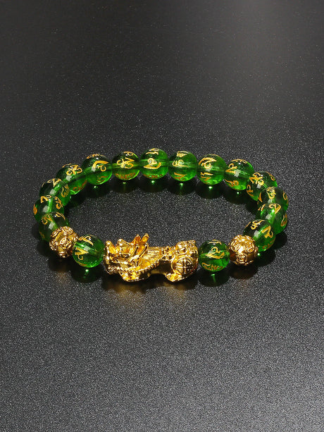 Green beaded bracelet with gold accents on a black background