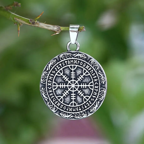 Silver Vegvisir pendant on a branch with a blurred green background