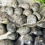 Collection of gray stones on a white surface with a decorative plate in the background