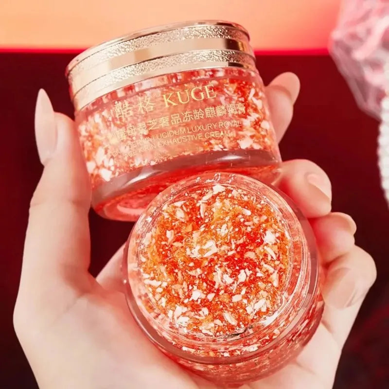 Hand holding a jar of KUGE luxurious cream with a red background