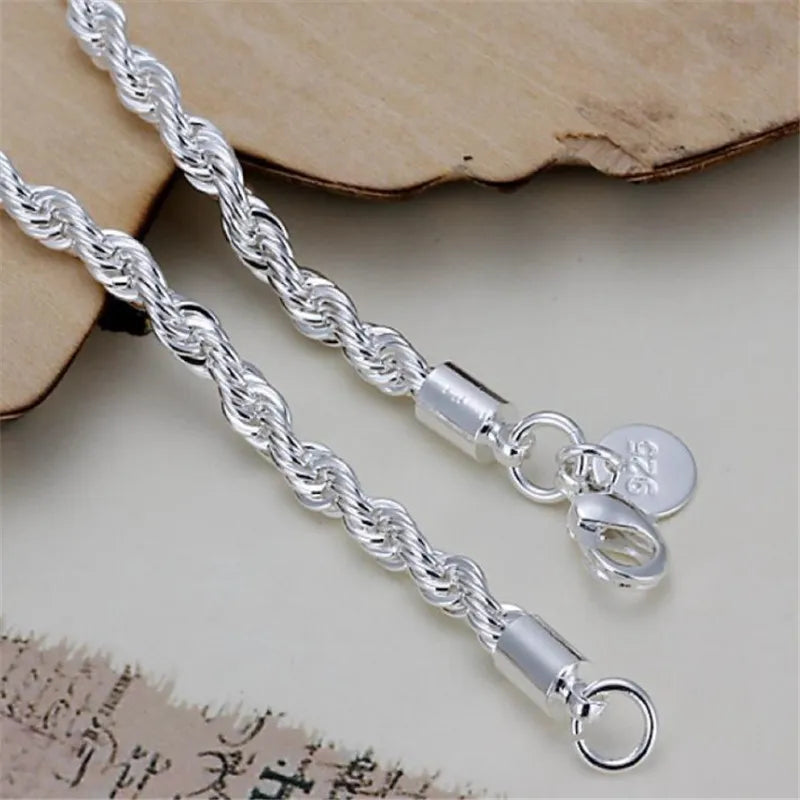 Silver rope chain necklace with clasp on a textured surface