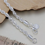 Silver rope chain necklace with clasp on a textured surface