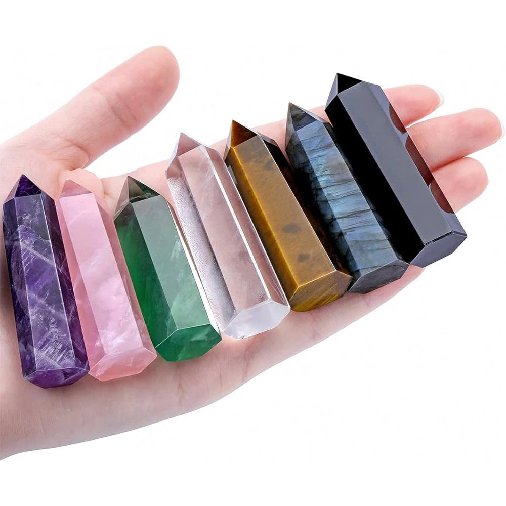 Hand holding a row of colorful crystal points on a white background