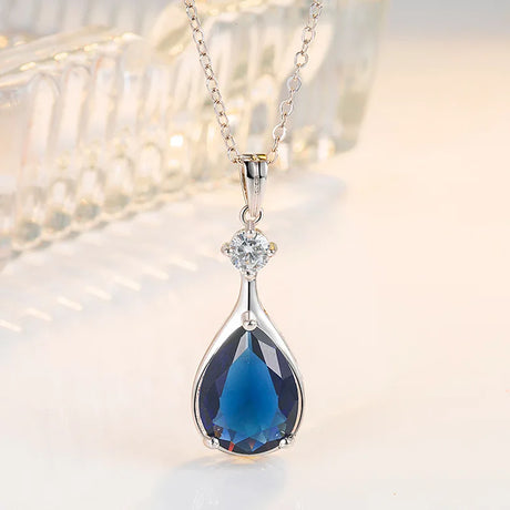 Blue teardrop pendant necklace with a diamond on a soft background