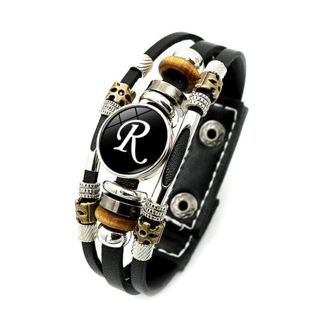 Black leather bracelet with decorative beads and a central black circle with a white 'R'.
