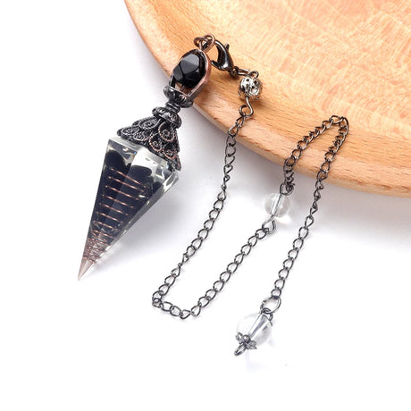 Crystal pendulum with chain on a wooden surface