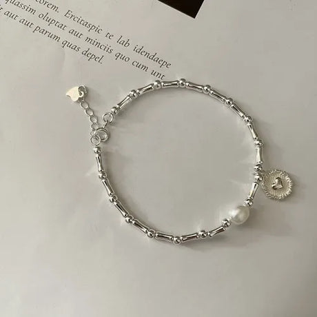 Silver bracelet with a pearl charm on a light gray background