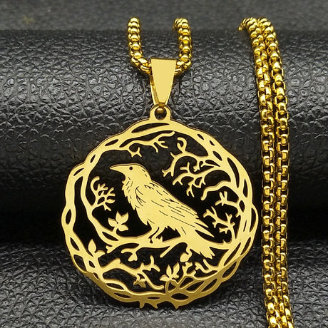 Gold bird pendant with chain on a black textured surface