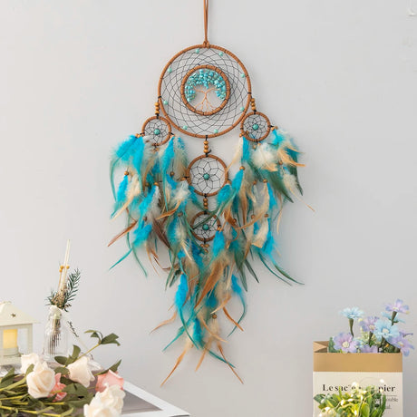 Decorative dreamcatcher with feathers on a light gray wall.